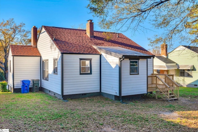 rear view of house with crawl space, a yard, a chimney, and roof with shingles