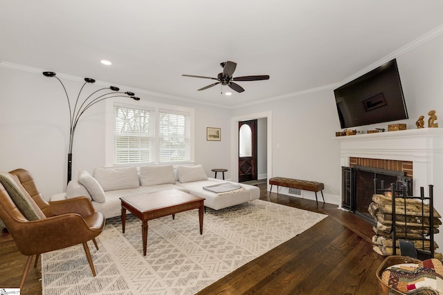 living room with recessed lighting, wood finished floors, a ceiling fan, ornamental molding, and a brick fireplace