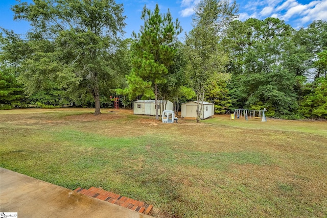 view of yard featuring a playground, an outdoor structure, and a storage shed