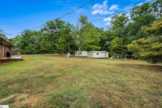 view of yard with an outbuilding, a storage unit, and a playground