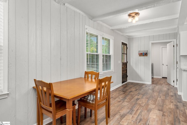 dining space featuring wood finished floors, beam ceiling, and baseboards