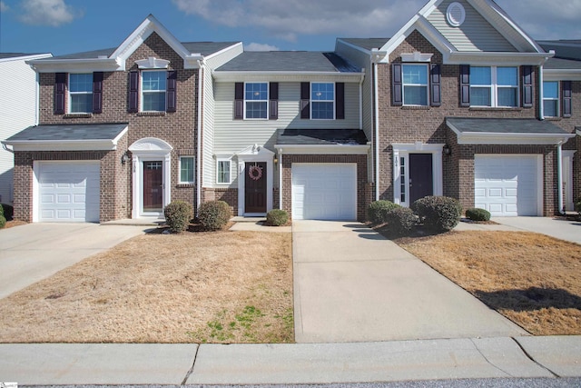 multi unit property with a garage, driveway, and brick siding