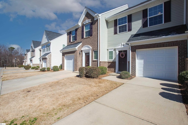 view of property featuring a garage, a residential view, brick siding, and driveway