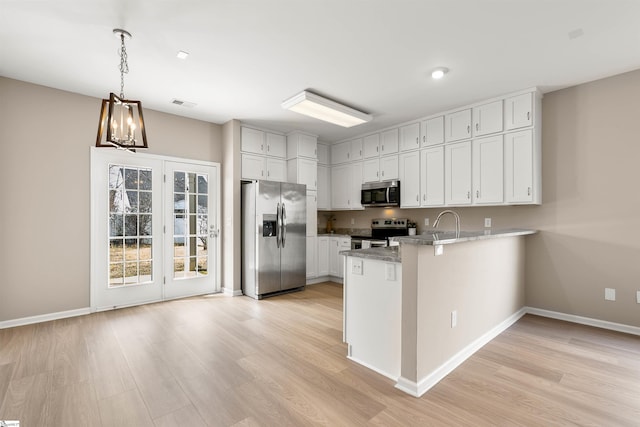 kitchen with a peninsula, white cabinetry, light wood-style floors, appliances with stainless steel finishes, and decorative light fixtures