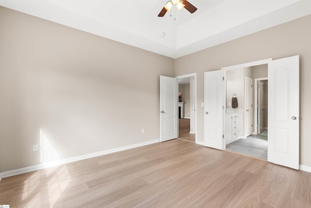 unfurnished bedroom with light wood-style floors, connected bathroom, baseboards, and ceiling fan