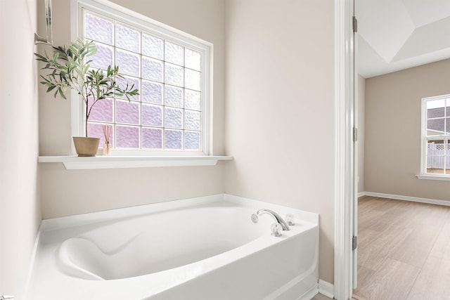 full bath with a garden tub, baseboards, and wood finished floors