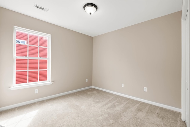 empty room with light colored carpet, visible vents, and baseboards