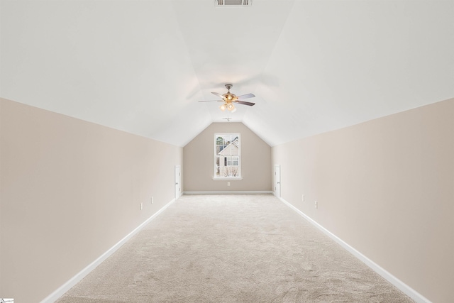 additional living space with light carpet, baseboards, visible vents, and vaulted ceiling