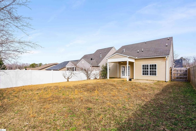 rear view of house with a patio area, a fenced backyard, and a lawn