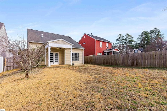 back of property featuring french doors, a fenced backyard, and a yard