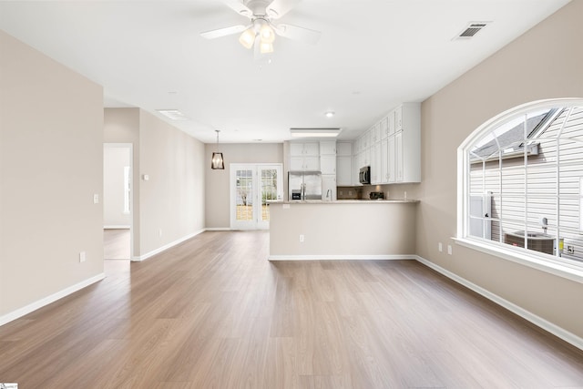 unfurnished living room featuring light wood-style floors, visible vents, baseboards, and a ceiling fan