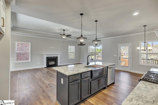 kitchen with dishwasher, an island with sink, open floor plan, light stone countertops, and a sink