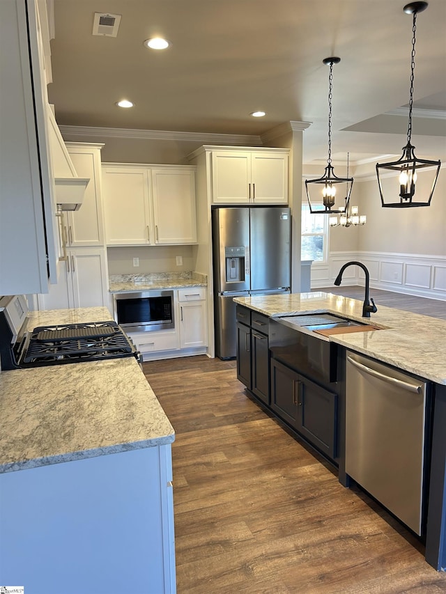 kitchen featuring appliances with stainless steel finishes, white cabinetry, pendant lighting, and a sink