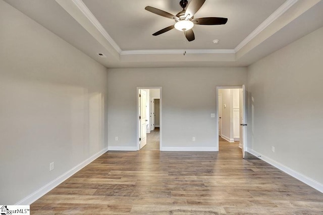 unfurnished bedroom featuring light wood-type flooring, baseboards, a tray ceiling, and ornamental molding