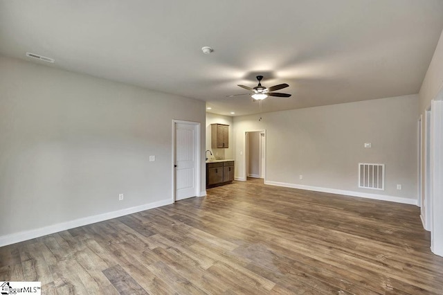 spare room with a ceiling fan, wood finished floors, visible vents, and baseboards