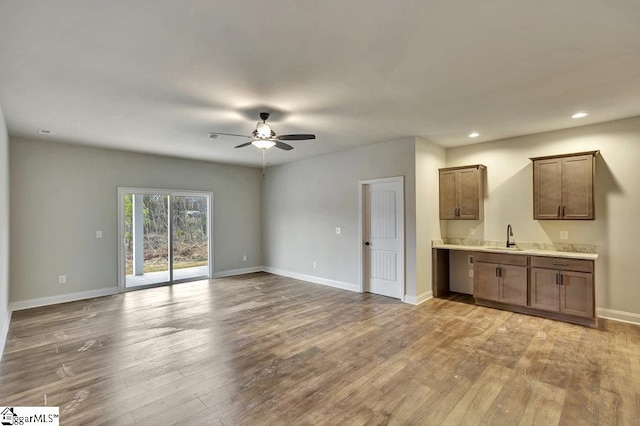 unfurnished living room featuring baseboards, ceiling fan, and light wood finished floors