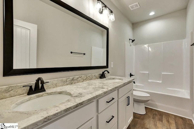 bathroom with bathtub / shower combination, visible vents, a sink, and wood finished floors