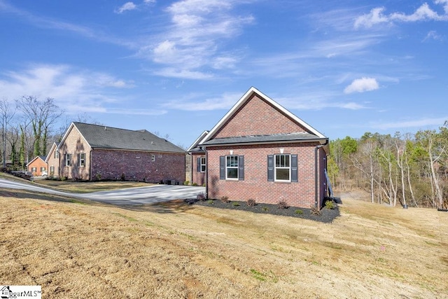 rear view of house featuring a yard and brick siding