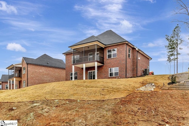 back of property featuring brick siding, a balcony, and central air condition unit