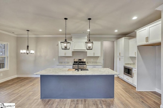 kitchen featuring a center island with sink, stainless steel appliances, and decorative light fixtures