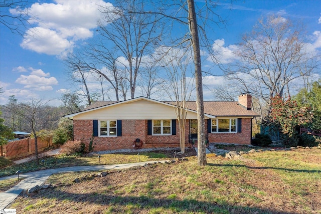 ranch-style home featuring brick siding, fence, a chimney, and a front lawn