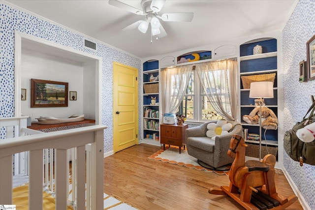 bedroom featuring ornamental molding, light wood-type flooring, visible vents, and wallpapered walls