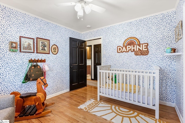 bedroom featuring wallpapered walls, baseboards, crown molding, and wood finished floors