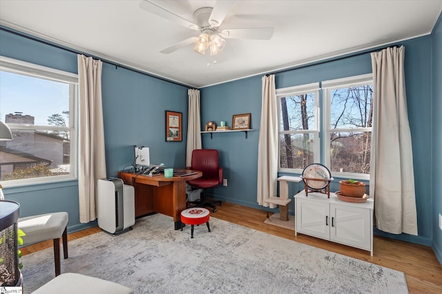 office space with baseboards, light wood-style flooring, and a ceiling fan