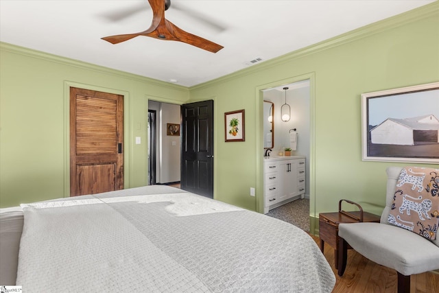 bedroom featuring ceiling fan, visible vents, ornamental molding, and connected bathroom