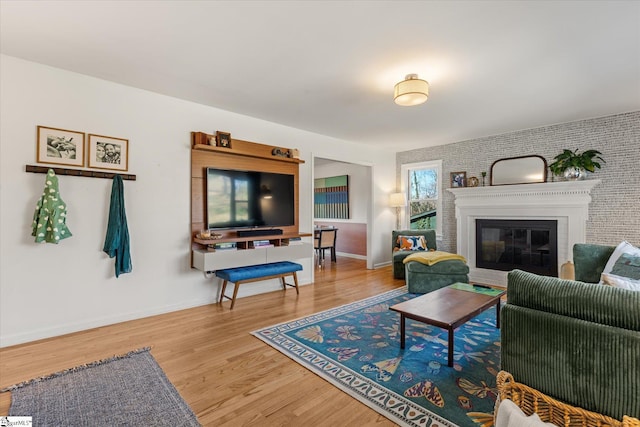 living area with a glass covered fireplace, wood finished floors, and baseboards