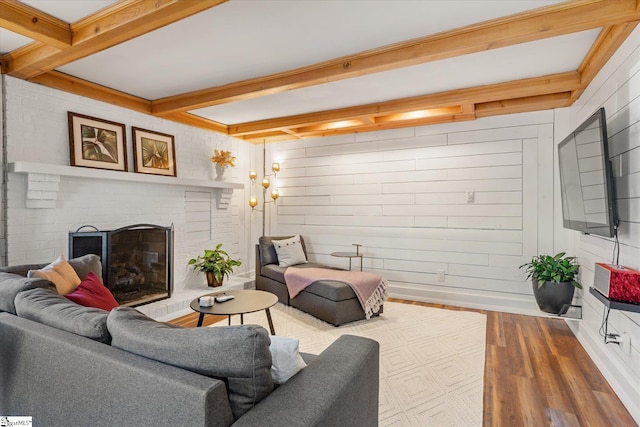 living area with beam ceiling, a fireplace, wooden walls, and wood finished floors