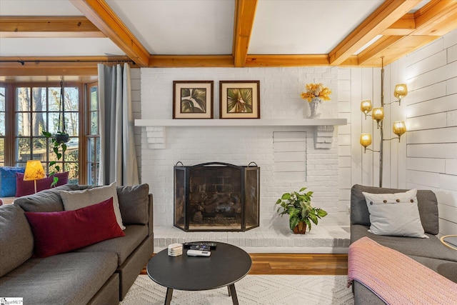 living room featuring beamed ceiling, a fireplace, and wood finished floors