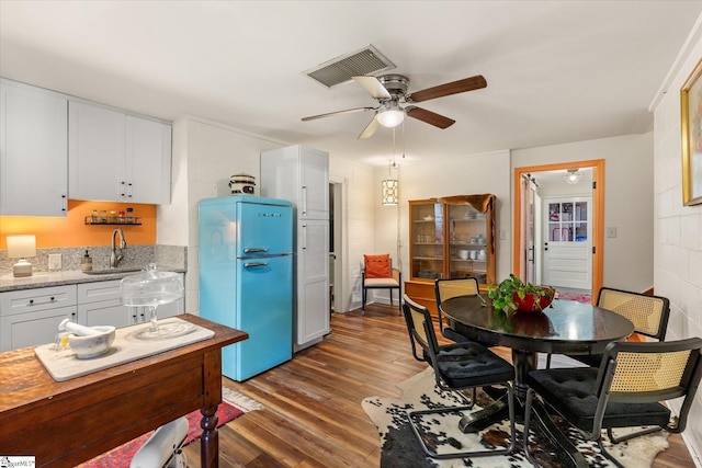 kitchen with visible vents, dark wood-type flooring, freestanding refrigerator, white cabinets, and a sink