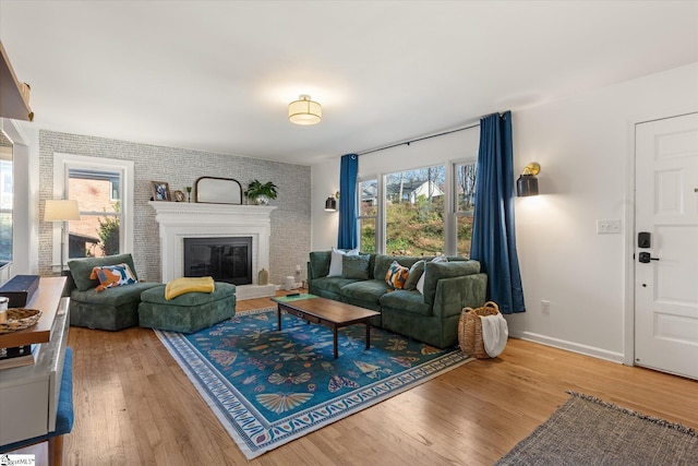 living room featuring a fireplace, baseboards, and wood finished floors