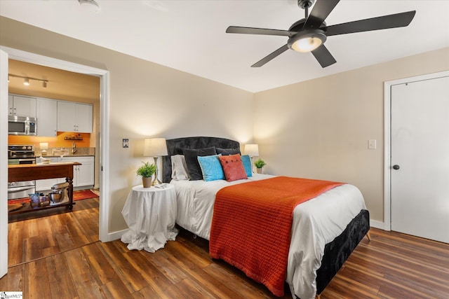 bedroom with dark wood-style floors, rail lighting, a ceiling fan, and baseboards