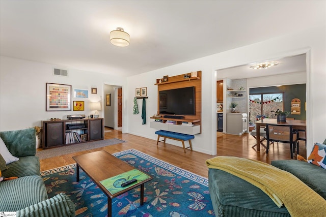 living area with baseboards, visible vents, and wood finished floors