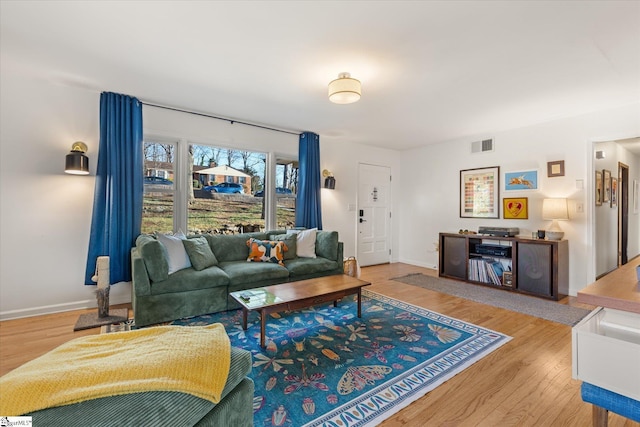 living room with baseboards, visible vents, and wood finished floors