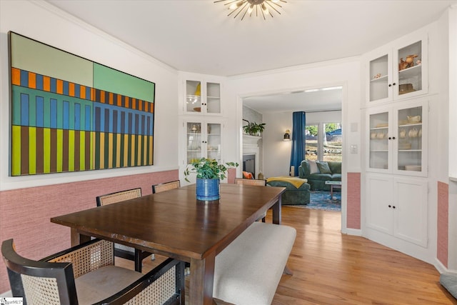 dining room featuring built in features, a fireplace, and light wood finished floors