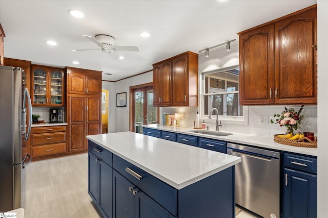 kitchen featuring stainless steel appliances, a kitchen island, a sink, light countertops, and glass insert cabinets