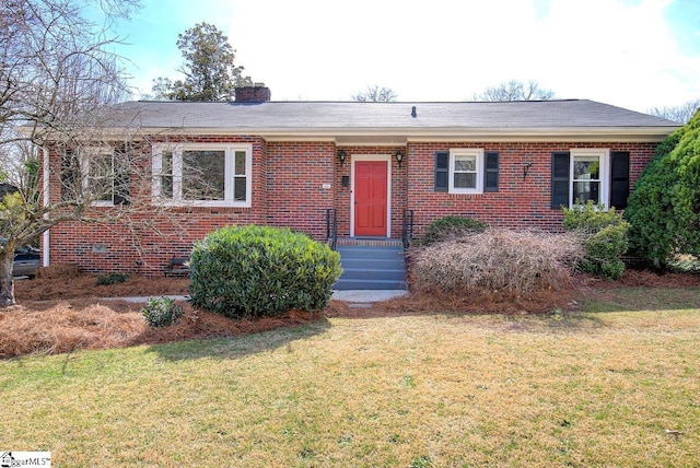 ranch-style home featuring brick siding, a chimney, and a front yard