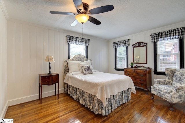 bedroom featuring ceiling fan, a textured ceiling, baseboards, and wood finished floors