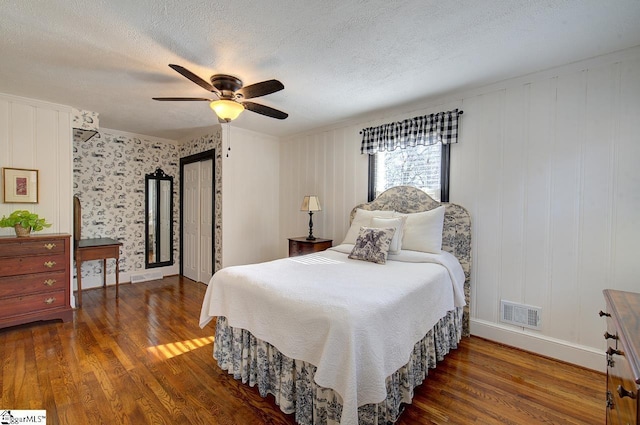 bedroom featuring dark wood-style floors, a textured ceiling, visible vents, and a ceiling fan