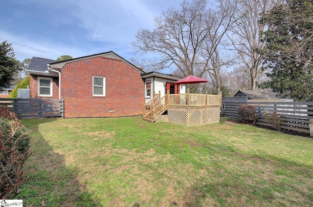 back of house with brick siding, a yard, crawl space, a deck, and a fenced backyard