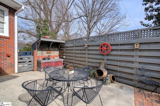 view of patio / terrace with a gate, fence, and outdoor dining area