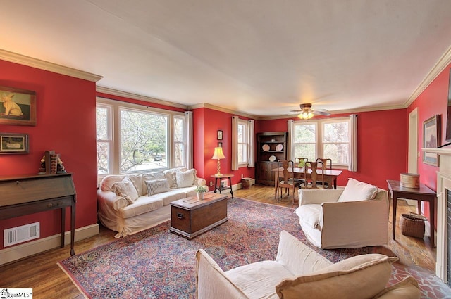 living room with baseboards, crown molding, visible vents, and wood finished floors