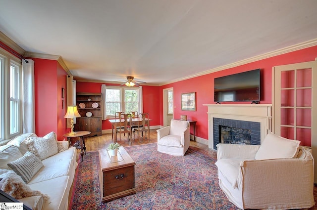 living room featuring baseboards, a fireplace, wood finished floors, and crown molding