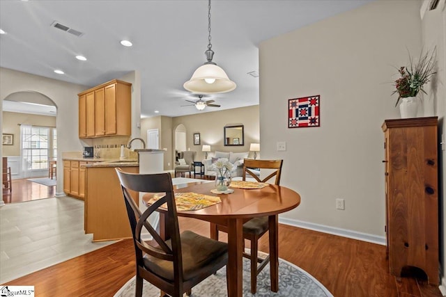 dining area with dark wood-type flooring, arched walkways, visible vents, and ceiling fan