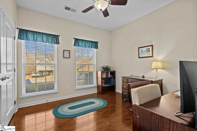 office space featuring dark wood-type flooring, visible vents, ceiling fan, and baseboards