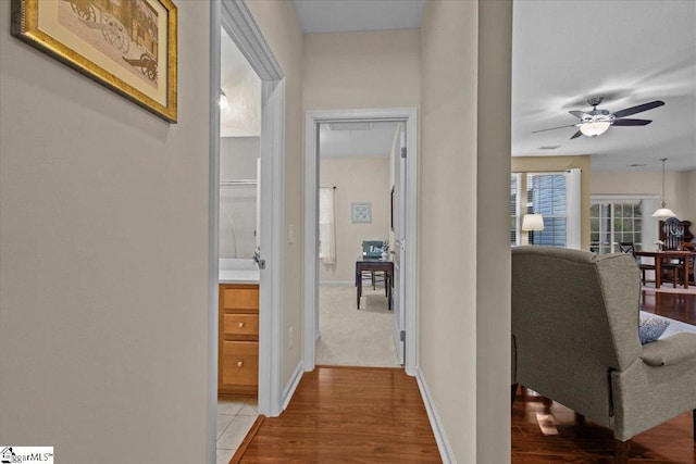 corridor with light wood-type flooring and baseboards