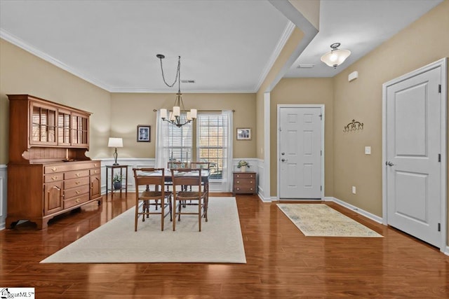 dining space with dark wood-type flooring, crown molding, a notable chandelier, and baseboards